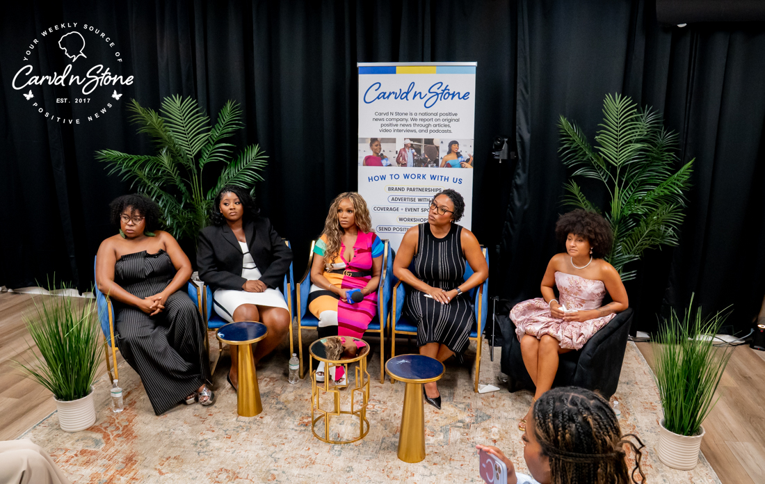 Five women seated on stage in front of a Cardi'd n Stone banner, discussing or presenting at an event.