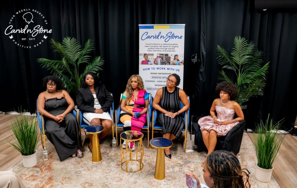Five women seated on stage in front of a Cardi'd n Stone banner, discussing or presenting at an event.