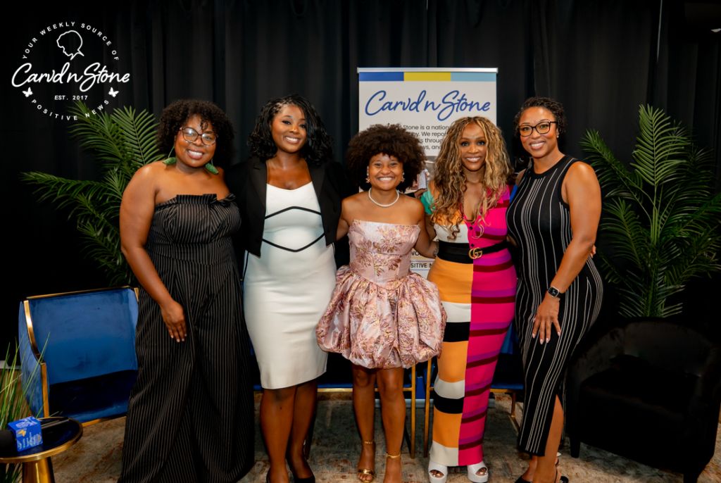 Five women posing in front of a Carvd N Stone backdrop, wearing stylish dresses and outfits.