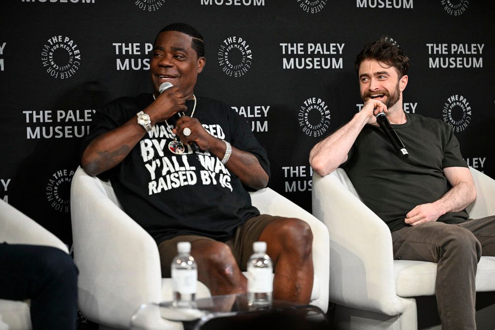 Two men, Tracy Morgan and Daniel Radcliffe, sitting on stage at The Paley Museum, with the text "THE PALEY MUSEUM" and "WASHED BY WALL WALL RAISED BY" visible.