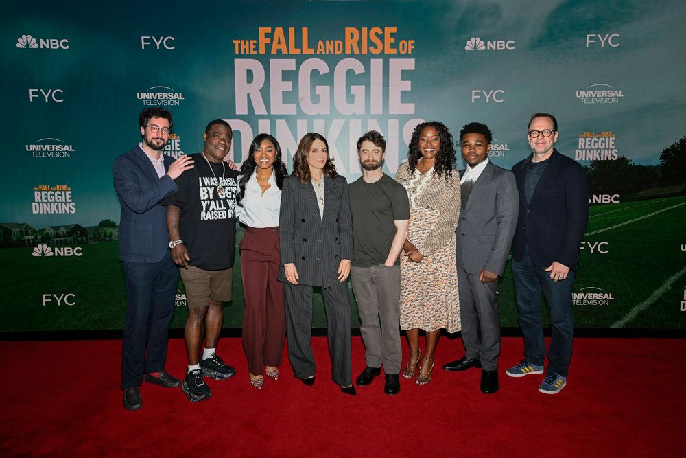 A group of people posing on a red carpet in front of a backdrop promoting "The Fall and Rise of Reggie Dinkins" on NBC and FYC.