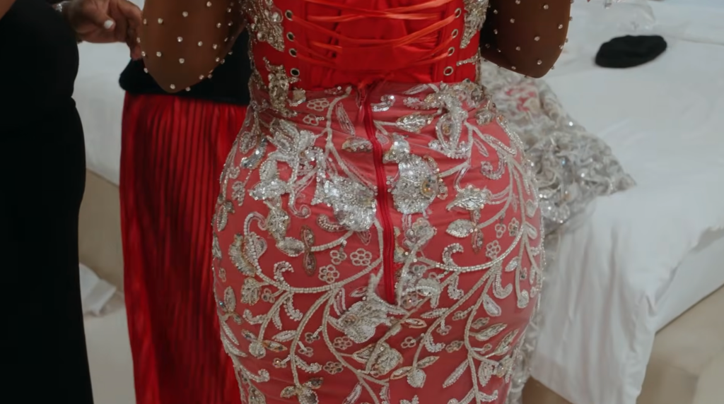 ’90 Day Fiancé’ Exclusive: Clip Ashia Sparkles & Shines In Ravishing Red For Her Nigerian Wedding–‘You Look Like A Barbie, Baby’ 5 A woman wearing a red, sequined dress with intricate floral embroidery and a lace overlay.