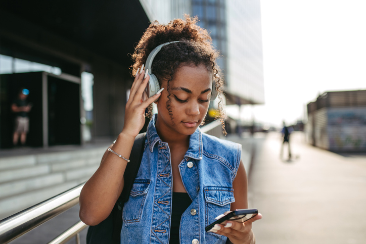 Portrait of gorgeous young woman in the city, headphones on head.
